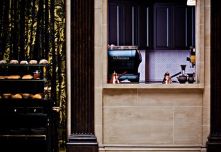 Even in the kitchen to dining room passthrough, the details are just right: a La Marzocco espresso machine and a peek of vibrant purple set inside a travertine windowbox.