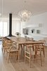 Modern home with Dining Room, Table, Chair, Hanging Fireplace, and Light Hardwood Floor. The interior scheme prevents clutter in a variety of creative ways, including concealing a heat pump in the walls and installing flush-fitting LED spotlights. The architects explain, “Since the redesign, the prevailing impression is one of spaciousness, the suffusion of light and simple elegance.”
A statement-making Hope Suspension Light by Luceplan is an elegant addition to the living area. The table, which was designed by the architects and fabricated by VHB Memmingen, is surrounded by CH24 Wishbone Chairs by Hans Wegner for Carl Hansen & Son. Photo of A Renovated Modernist Oasis in the French Riviera That Has Hosted Picasso and Royalty