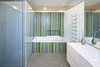 Modern home with Bath Room, Drop In Tub, Mosaic Tile Wall, and Ceramic Tile Floor. Glass elements not only allude to the ocean, but also lend a fresh look to some of the rooms. Here, Trend glass mosaic tiles brighten up the bathroom. Axor fixtures from Hansgrohe stand next to a minimalist radiator from Zehnder. Photo of A Renovated Modernist Oasis in the French Riviera That Has Hosted Picasso and Royalty