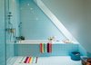 Modern home with Bath Room and Drop In Tub. Six-inch-square blue tiles cover the walls and floor of the girls’ upstairs bathroom. The towels and rug are also by H&M Home. Photo of Blue Mood: 9 Creative Ways to Use Color