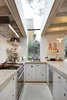 Modern home with Kitchen, Concrete Floor, Concrete Counter, Drop In Sink, Pendant Lighting, Range Hood, Range, and Open Cabinet. A sturdy concrete countertop curves around the entire length of the kitchen, finished in a texture Webster describes as “bug splattered.” Despite the unappetizing name, it works well for rolling out dough. Its circular motif reappears in the custom cabinets’ finger pulls, which also help ventilate the cupboards. The fixtures are from Kubus and the appliances are from Miele. Photo of Airy Kitchen Additions