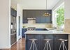 Modern home with Kitchen, Pendant Lighting, Range Hood, Refrigerator, and Medium Hardwood Floor. The kitchen sports blue-gray cabinets and Azulej tiles by Patricia Urquiola for Mutina. The Currys keep an eye on the backyard through a large Pella window, situated above a sink with a Sensate faucet from Kohler. The range is by BlueStar. Photo of Airy Kitchen Additions