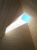 Modern home with Windows and Skylight Window Type. At the entry looking upward towards a Velux skylight, a vertical "sleeve" is made of stacked end grain plywood. The theme of vertical and horizontal architectural elements providing different environmental perspectives carries through to the rest of the home. Horizontal forms look out to the lake, while the vertical columns look up the sky. Photo of An Abstract New England Lake House That Sinks Into the Land