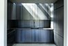 Modern home with Kitchen and Metal Cabinet. The clients and design team chose to forego an open floor plan in favor of defined, separated spaces. In this scheme, the vertically oriented spaces act as a cinematic "hard-cut" to their horizontal counterparts. The custom hot rolled steel kitchen, one of these vertical transition spaces, receives light from above through a Velux skylight. A GE Profile Induction cooktop and oven and Miele refrigerator complete the space. Photo of An Abstract New England Lake House That Sinks Into the Land