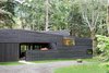 Modern home with Exterior, House Building Type, Cabin Building Type, and Wood Siding Material. “From the street, it appears as a rectangular building with sloping shed roofs, but this is actually an illusion,” Hutchison notes. “The floor plan is actually U-shaped, wrapping around an entry courtyard that is contained by the continuous west facade.” A standing seam metal roof by Custom Bilt Metals blends in with the cedar siding. Photo 2 of Courtyard House on a River