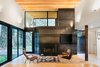 Modern home with Living Room, Light Hardwood Floor, Chair, and Standard Layout Fireplace. “From the courtyard, you then enter the house proper, directly into the main living room,” Hutchison says. “From this room, you have a panoramic view looking out through the trees to the river, or back into the courtyard.” The wood-burning fireplace, from Majestic, is clad in steel panels. Eames Molded Plywood lounge chairs sit side-by-side in the living room. Photo 4 of Courtyard House on a River
