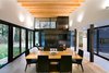 The home’s interior design was intentionally simple: access to light and views were a main priority. “The roof in this room slopes gradually up to the south, providing a light monitor that brings in southern light filtered through the trees, while providing a framed view of the tops of the trees beyond,” Hutchison says. Plank flooring by United Tile and Edge wall sconces by Belfer unite the living and dining spaces. Photo 5 of Courtyard House on a River modern home