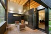 Modern home with Outdoor, Small Patio, Porch, Deck, Wood Patio, Porch, Deck, and Back Yard. After years of visiting the area as vacationers, one couple builds this striking home for their retirement outside Greenwater, Washington. A fireplace can be used on the rear patio and in the living room, making it feel like one cohesive space. Ipe planks, the same wood that’s used in the front courtyard, cover the floor. Photo 9 of Courtyard House on a River