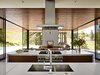 Modern home with Kitchen, Wood Cabinet, Range, Undermount Sink, and Range Hood. All appliances in the kitchen are from Thermador, save for a Miele dishwasher. Bright white Caesarstone bounces yet more light into the space. Photo of These Modern Glass Homes Shatter Conventions