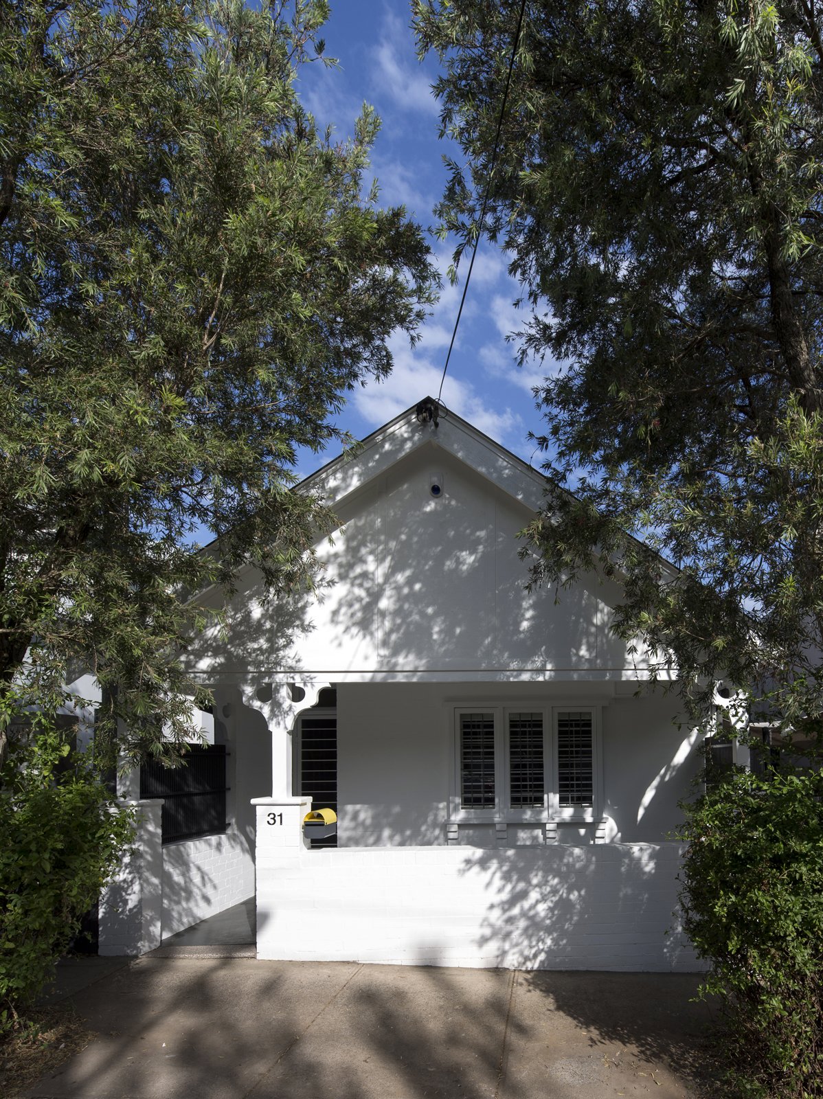 The façade of the interwar dwelling was painted bright white and left largely unchanged, with a sole burst of color coming from a yellow DesignByThem 