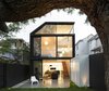 The addition’s two stories of cedar-framed sliding doors and window provide generous views of the house’s prized jacaranda tree. The addition’s polished concrete floor and white cladding extend into the garden, drawing occupants to the serene rear porch. There, they can relax on stools designed by Alvar Aalto and Charles Wilson while admiring the luscious greenery. Photo 3 of Cosgriff House modern home