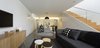 The extension’s lower level flows uninterrupted from the garden to the kitchen. Storage units hidden under the staircase give the living spaces an uncluttered feel. A Skygarden pendant by Marcel Wanders hangs over Snow 300 dining chairs by James Richardson, providing light in those rare hours when sunlight isn’t streaming in. Photo 4 of Cosgriff House modern home