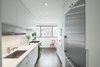 Modern home with Kitchen, White Cabinet, Refrigerator, Ceramic Tile Backsplashe, Range, Wall Oven, Recessed Lighting, Dark Hardwood Floor, Undermount Sink, and Marble Counter. The homeowners, who are avid cooks, worked with a design duo and contractor for the home's renovation. To make the kitchen seem larger than it is, the team decided to place the largest cabinets and appliances near the entryway, making less clutter toward the window.
Photo of Storage-Savvy Apartment Renovation in NYC
