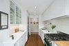Modern home with Kitchen, Range, and Ceramic Tile Backsplashe. The kitchen combines varying storage types, from white lacquered cabinets and glass-fronted ones to a floating shelf above the sink. The countertop is Calacatta Caldia marble, and the subway tile that clads the backsplash is from Heath Ceramics. Photo of Storage-Savvy Apartment Renovation in NYC