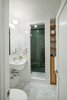 Modern home with Bath Room, Ceramic Tile Wall, and Enclosed Shower. An updated bathroom features a mix of tiles: Carrara marble tiles on the floor, green subway tiles from Heath Ceramics on the inner shower walls, and white subway tiles from Daltile on the exterior walls. The fixtures are from Grohe. Photo of Storage-Savvy Apartment Renovation in NYC