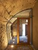 Dramatic floor lighting on this glass wall, custom fit within the curve of a carved-out stone wall, provides simple beauty in material contrast. "In such small spaces, it's often better to integrate the furniture and fixtures into the room," says de Meuron. Photo 5 of Scaiano Stone House modern home