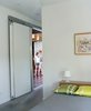 Modern home with Bedroom, Bed, and Table Lighting. From the simple, pared-down bedroom, a sliding door reveals the wood-paneled living area, where bright colors and varied textures rule. Photo 16 of New Grass Roots