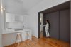 The apartment’s minimalist aesthetic continues in the kitchen, where functional but sleek fixtures were installed. To the right, a charcoal-gray sliding wall signals the entrance to the flat’s private quarters. Photo of Minimal Apartment in Lisbon Divvied Up by Sliding Doors modern home