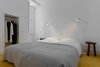 Rocha replaced unsightly carpeting in the master bedroom with yellow ochre hydraulic tiles that harmonize with the stark white walls and soft gray bedspread. The south-facing windows were kept small to ensure privacy, but they still let in plenty of light. Photo of Minimal Apartment in Lisbon Divvied Up by Sliding Doors modern home