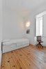 A tiny wall nook holds books in the spare bedroom, where the original wood floors take the spotlight. Photo of Minimal Apartment in Lisbon Divvied Up by Sliding Doors modern home