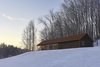 Durability was an important factor in the building’s exterior. The architect selected materials, such as weathering steel for the roof and charred cedar for the siding, which would age gracefully. The deep browns and reds also blend into the forested landscape. Photo of Off-Grid Retreat modern home