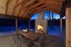 Douglas fir columns frame views from the porch, located just adjacent to the living, dining, and kitchen space. A sandstone fireplace bookends this space, creating a sheltering and warming effect. Photo 4 of Off-Grid Retreat modern home