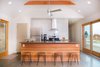 The kitchen island, also Douglas fir, showcases the material’s rich striations and color variations. Behind the kitchen are two bedrooms and a single bathroom. A large open air pavilion, built concurrently with the cabin, can be seen from the windows on the right. Photo 7 of Off-Grid Retreat modern home