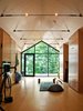 Modern home with Living Room and Medium Hardwood Floor. The client, a life-long practitioner of yoga, was tired of the drab, enclosed yoga studios he usually used. Instead, he desired a beautiful space that connected to the outdoors. Thanks to its views and simple interior finish, the client described it as supremely tranquil and a warm ‘womb-like’ environment. Photo of High-Tech Prefab Outbuilding is a Surprisingly Peaceful Retreat