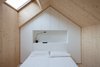 Modern home with Bedroom, Bed, Table Lighting, Light Hardwood Floor, and Shelves. Each bedroom is designed to replicated a mini house, and follows the roof's pitch. A skylight lets in light. A custom unit made of white-painted MDF panels provides necessary storage. Photo of Our Favorite Bedrooms