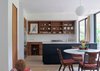 Modern home with Marble Counter, Light Hardwood Floor, Wood Cabinet, Pendant Lighting, Recessed Lighting, Range, Marble Backsplashe, Drop In Sink, Dining Room, Table, and Chair. For the kitchen, American cherry wood was used to create cabinets that establish a warm and sturdy tone. Each piece of lumber was purchased at auction by the Brillharts and stored in New Hampshire, before being shipped to Miami and milled on site. The wood island is painted black to provide a point of visual contrast. Photo 4 of Brillhart House