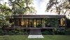Modern home with Exterior, Glass Siding Material, Flat RoofLine, Wood Siding Material, and House Building Type. Between the front and rear exteriors, over 800-square-feet of patio space extend the living areas into the outdoors. From this angle, the references to Florida cracker architecture are obvious. The sleeping quarters are connected via a central corridor and kitchen to the living space on the other end of the building, a modern interpretation of the classic dogtrot house. Photo 8 of Brillhart House