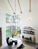 Modern home with Living Room, Chair, and Pendant Lighting. Concerned about the chemicals involved in laminate flooring, the couple chose to leave the concrete slab, the foundation of the home, exposed, almost eliminating flooring expenses. A local craftsman made the windows, using Texas pine for framing. The floor-to-ceiling windows, Pavonetti says, reduces the couple's need for lights. Photo of This Bright, Personality-Filled Home Was Built on a Budget in Austin