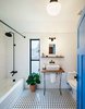 Modern home with Bath Room and Subway Tile Wall. To create a bit more texture in the kitchen and baths, the couple added classic checkered tiles from the local hardware store—an inexpensive option that broke up the polished concrete floors spanning the rest of the house. Pavonetti designed and built the pedestal sinks using reclaimed cedar siding. Photo of This Bright, Personality-Filled Home Was Built on a Budget in Austin