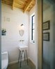 Modern home with Bath Room, Concrete Floor, Pedestal Sink, One Piece Toilet, Wall Lighting, and Wall Mount Sink. The sink in the half bath was special-ordered from Home Depot and Pavonetti designed the base to give the basin a snug fit. He built it out of a steel rod and painted it with black shoe polish. Photo of Bright, Personality-Filled Home Built on a Budget in Austin