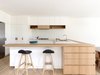 In the kitchen, black-cushioned bar stools by Erik Buch pop against the blonde wood counters, custom white melamine cupboards, and milky ceramic tile backsplash. The kitchen sink is by Franke, the faucet by Grohe, and the fridge by Liebherr. Photo 5 of Lush Hill modern home