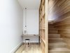 A central winding staircase connects the original house to the new addition. Exposed framing flanking the staircase creates an intimate study with plenty of shelving space. A Nud pendant light from Great Dane hangs above the built-in desk. Photo 6 of Lush Hill modern home