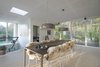 Smithfield pendant lights by Jasper Morrison for Flos illuminate the dining table. Natural wood floors and neutral hues create a spare, yet warm, aesthetic. Photo 4 of Villa R modern home