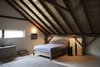 Modern home with Bedroom and Bed. With its open-joisted, gabled ceiling, the upstairs bedroom is cozy but bright. Bedside tables from Kartell and Tizio Lamps from Artemide flank the bed, while a midcentury credenza, purchased at Old Soul Antiques sits beneath the window. Photo of A Slice of Scandinavian Design in the Catskills