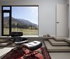 Modern home with Living Room, Ottomans, Concrete Floor, Recliner, and Rug Floor. The clients intend to retire to the house. They asked that rooms be constructed flexibly on a non-domestic scale. This one, with an Eames lounge and floor-to-ceiling glass windows, frames a serene mountain vista like a painting. Photo 4 of Lake Hawea Courtyard House
