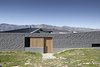 The protective wall is broken with small apertures, like this wood-panelled door that slides back to allow entry. Photo 6 of Lake Hawea Courtyard House modern home