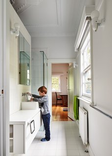 In the main bathroom, Art Deco crown molding reminds residents of the house’s past. New fixtures include white laminate cabinets and sinks and faucets by Roger Seller.