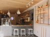 Modern home with Dining Room, Stools, Bar, Pendant Lighting, Ceiling Lighting, Track Lighting, and Shelves. Tommy and Chris Newbury started serving Réveille Coffee from a stripped down food truck, and have quietly grown into their second brick-and-mortar location in the Castro. The brothers describe their design aesthetic as "clean Californian modernism" and the Castro location lives up to their vision. Relying on cues from local metal and woodworker Jeff Burwell, the space is peppered with white metal chairs and stools, and showcases a stunning installation of stacked split wood at the rear of the cafe. Mexican cement tiles make up the eye-catching patterned backsplash of the coffee bar, and the shop takes advantage of its Castro Street frontage with the creation of an intimate and inviting front patio. 4076 18th Street Photo of The 10 Best-Designed Coffee Shops in San Francisco