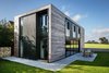 The house, which is located near Oxford, is clad in cedar. Composite timber and aluminum windows maintain the house’s connection with the countryside, as does the generous patio that wraps around two of its sides. Photo of Sandpath modern home
