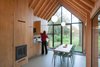 Modern home with Kitchen and Wood Cabinet. Fine wood craftsmanship defines the dwelling's interior, where all the facilities—from the kitchen cabinets to the fireplace to the bathroom—are integrated into a single oak wall, handmade by van Norel. He also made the dining table, which is paired with Philippe Starck master chairs—the only ready-made items in the space other than fixtures and appliances. Photo 6 of Utrecht Cabin