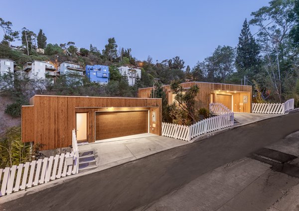 The two separate structures were given a visual unity by cladding them with a specially fire-treated cedar siding on the exterior. The white picket fence is another visual tie between the properties.