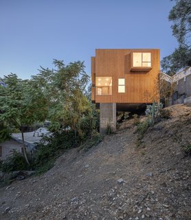 Both the front door and garage are accessible from street level. The floor is cantilevered out over a concrete pile foundation and garden far below.