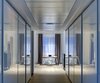 Another of the home’s transitional spaces is the walk-in closet in the master wing. Challenged by the lack of windows in the transitional areas, the closet doors are clad in white glass from Salice America to help bounce light and maximize reflection. Photo of A Bright Brooklyn Loft with an Envy-Inducing Walk-In Closet modern home