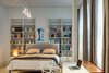 In the master bedroom, a small workstation is accented by a Philippe Stark desk chair, and repurposed white shelving offers generous display space. Ten foot ceilings and expansive windows add to the open and airy feel of the room. Photo of A Bright Brooklyn Loft with an Envy-Inducing Walk-In Closet modern home