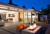 Modern home with Exterior, Mid-Century Building Type, and House Building Type. In the outdoor living area, orange Primary Pouf stools by Quinze & Milan and an ipe bench surround the central fire pit. An outdoor kitchen neighbors its interior counterpart. In addition to a grill, it accommodates a table and bench by Kayu. Photo of Modern Master: Joseph Eichler