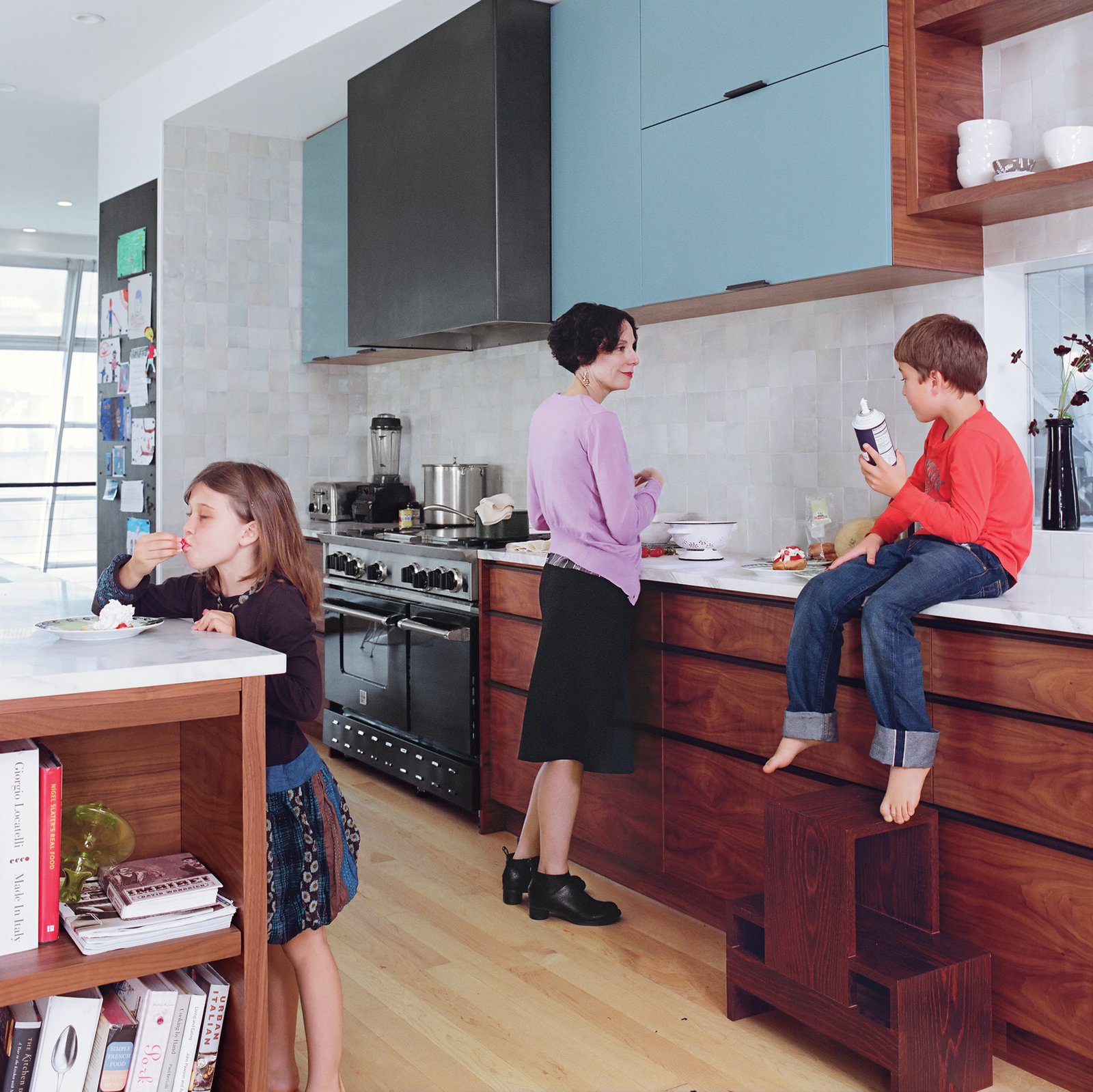 Sasha samples berries at the island while Wes, perched on the counter next to Deborah, clutches the whipped cream—similar in color to the backsplash, made of traditional Moroccan tiles and available through Emory & Cie.